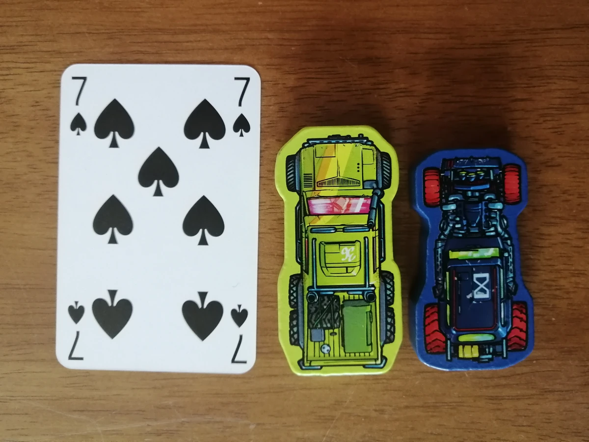Car tokens next to a standard playing card. The cars vary slightly in size but are roughly three quarters the height of the card and just over half the width.