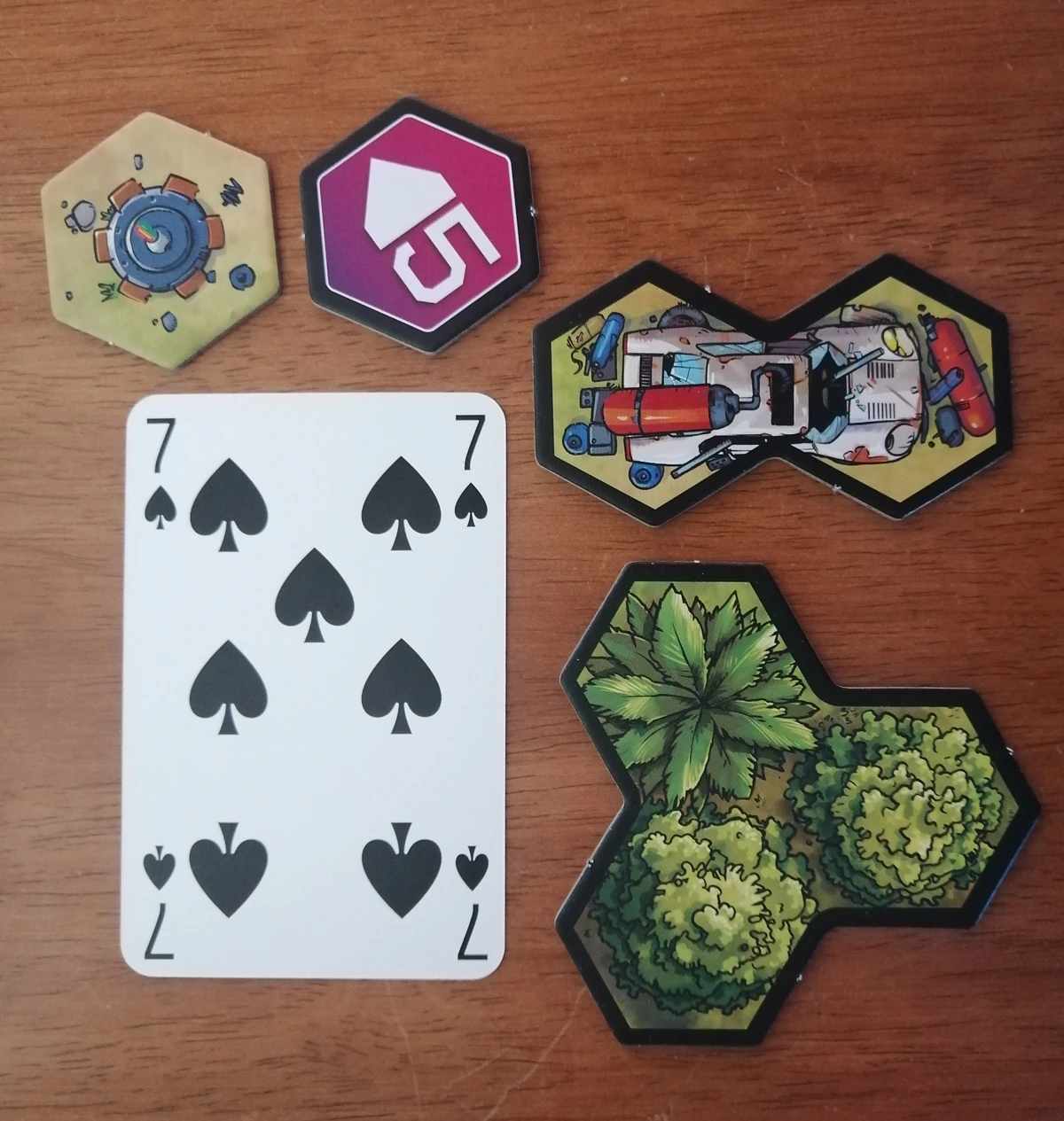 Item, gate and obstacle tokens next to a standard playing card. The tokens are hexes and some obstacles are multiple hexes together. The hexes are just over half the width of the playing card.