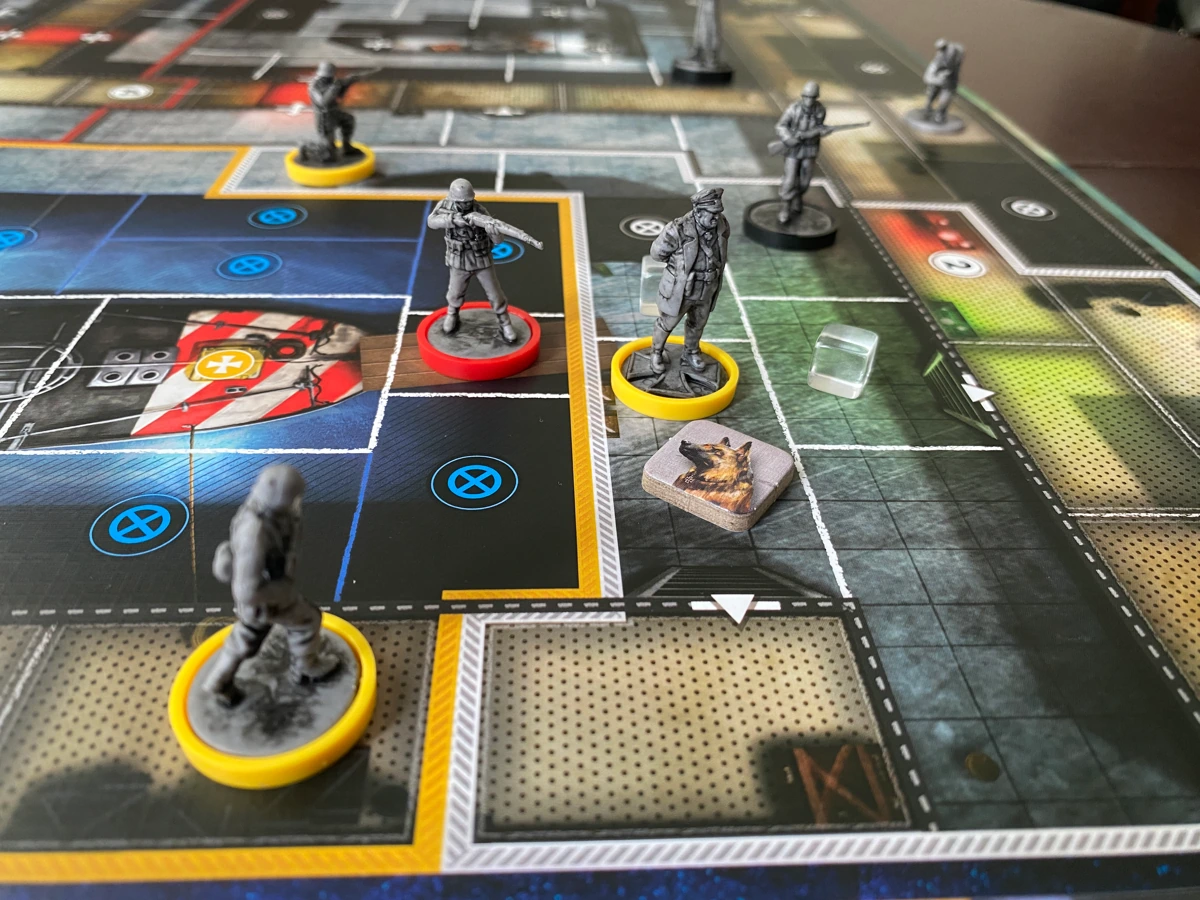 A close-up of the game board showing miniatures and tokens on the board in different spaces. Spaces vary in size and in the smallest of spaces the miniatures fit with a few millimeters of room around them.