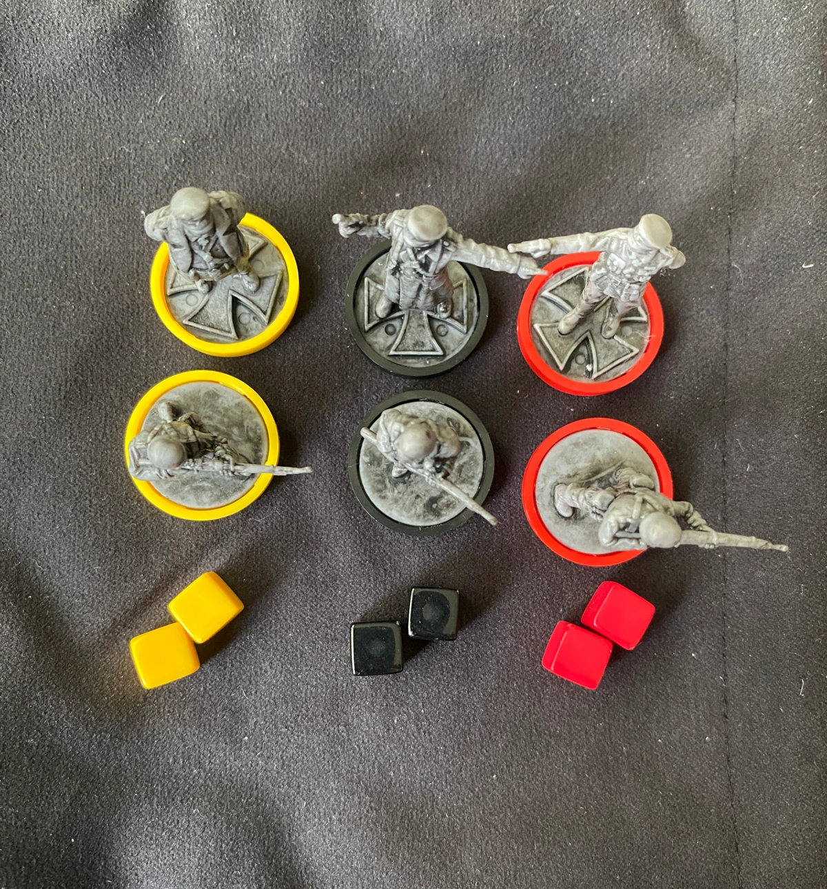 A selection of defender miniatures with their coloured base clips and their corresponding cubes. The three colours are yellow, black and red.