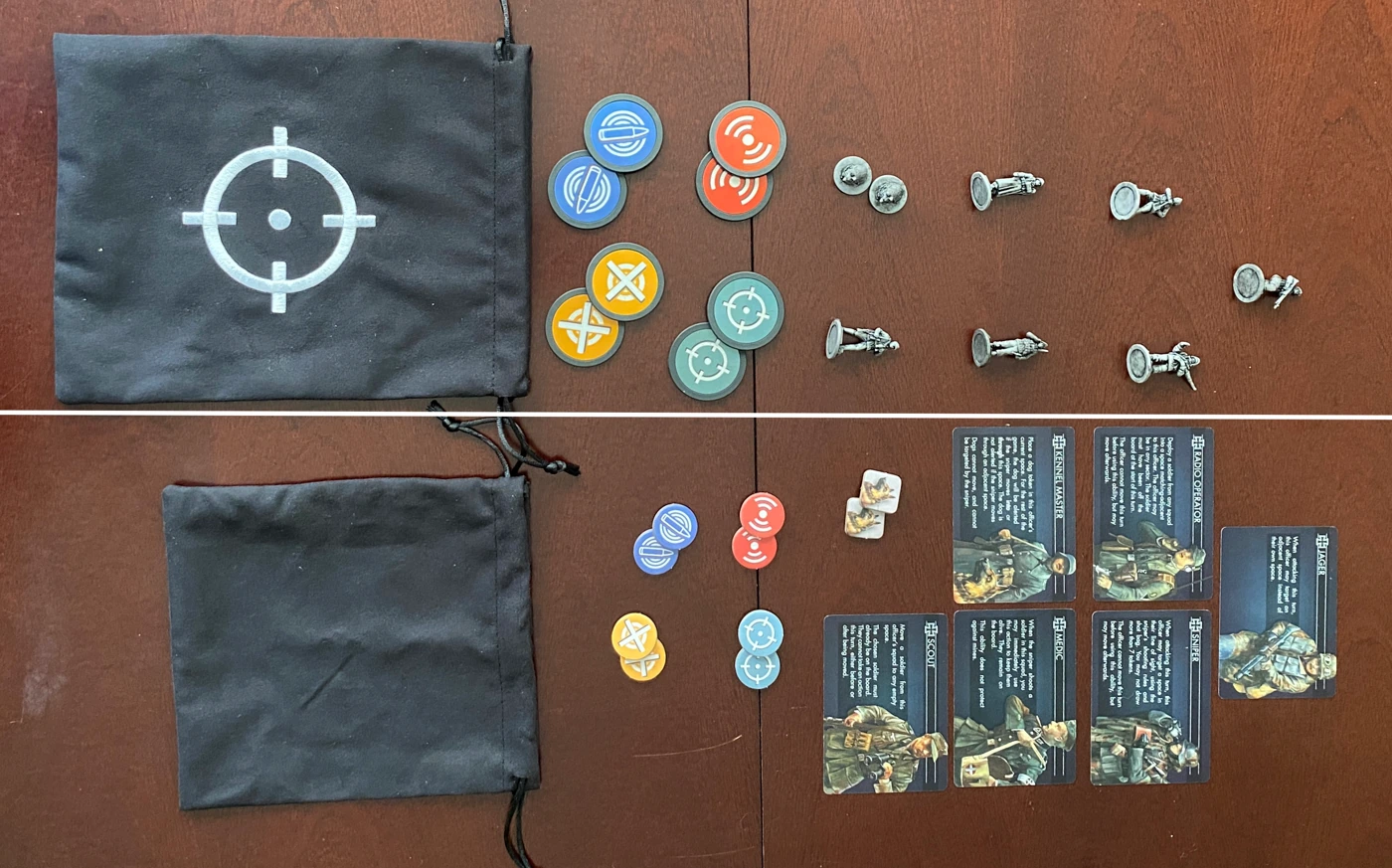 Side-by-side of the deluxe components and the standard components. In the deluxe version the cloth bag is bigger and features an embroidered shot symbol, the punchboard shot tokens are replaced with clay poker tokens, and there are miniatures for each of the defender specialists and the dog tokens.