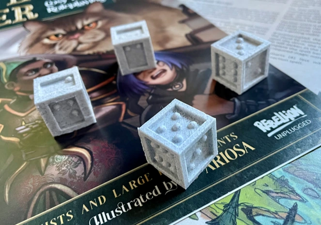 Photo of 3D printed tactile dice. Two of them are letterboxed with braille numbers, and the other two use standard pips, but are embossed not debossed.